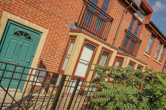 A house in the sunshine with a teal coloured door