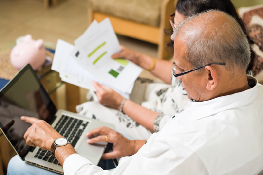 A man and woman analysing their letters whilst pointing to the laptop screen