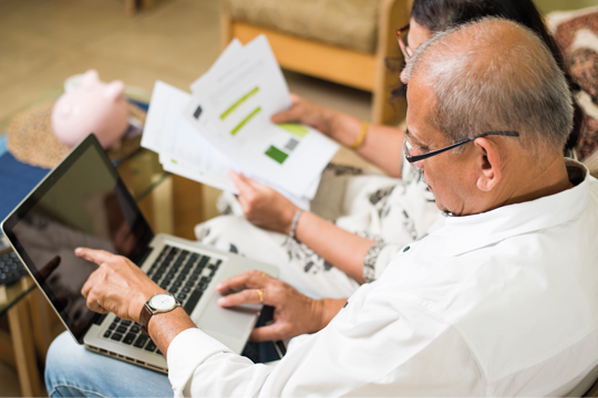 A couple checking their computer with their letters to the side