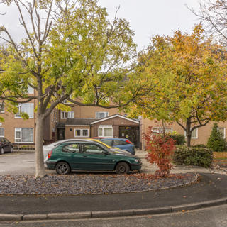 Front of Alderfield property with cars parked and trees in the garden