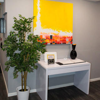 White table next to a plant pot and yellow poster hanging above