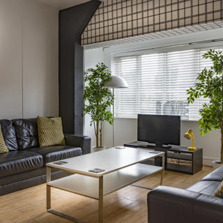 Black couch with a white patterned cushions and wooden table