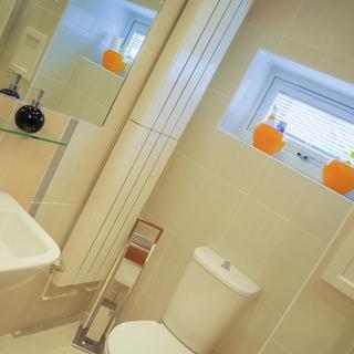 White interior bathroom with two orange toothbrush holders on the windowsill