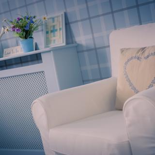 White chair with cream coloured pillow and blue table to the left