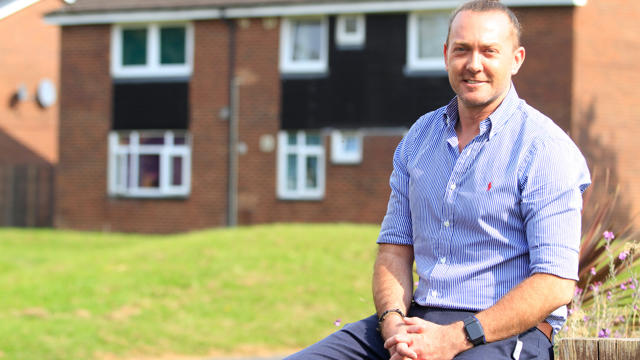 Irwell Valley Employee sitting on fence near houses