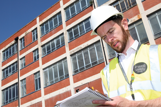 Irwell Valley Employee in a hardhat and high vis looking at the note pad