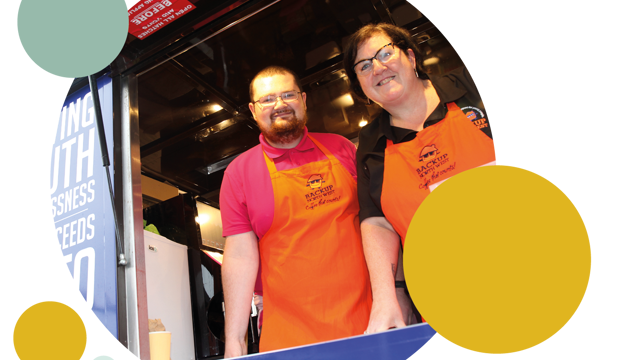 A woman and a man in orange aprons working in the coffee van 