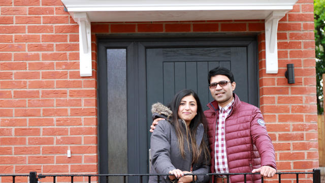 Couple posing for a picture in front of their new property
