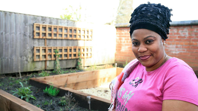 Woman posing in front of the plants which she has grown 