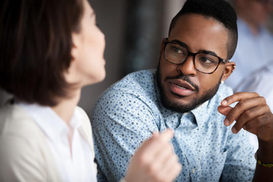 Man wearing glasses explaining something to a woman