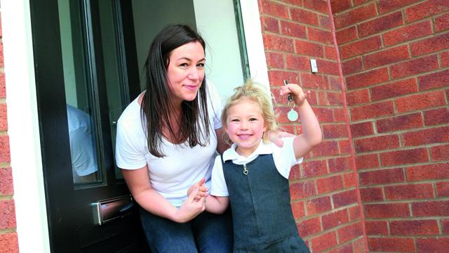 A woman and her child showing off their keys to the new house