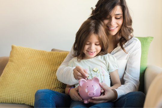 A woman with her child putting coins in the piggybank 