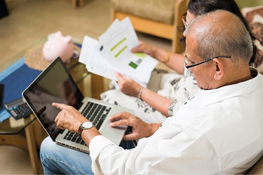 A man and woman analysing their letters whilst pointing to the laptop screen