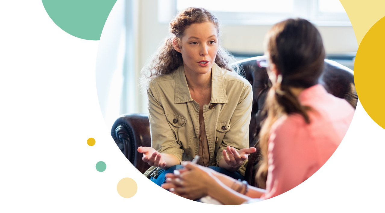 Two woman talking to each other on a leather chair