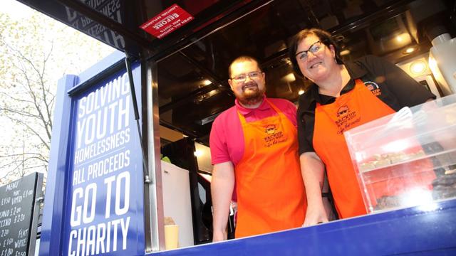 Two people in the café van and orange aprons