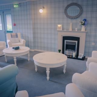 Blue and white chairs near a fire place and coffee tables in the communal area