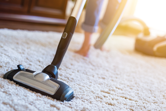 A woman hoovering her carpet 