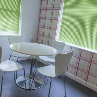White chairs and table with a patterned room and green blinds