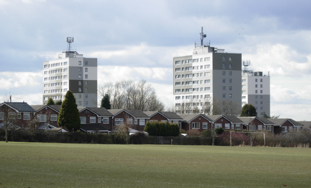 Three council flats in Manchester pictured above the houses and football pitch